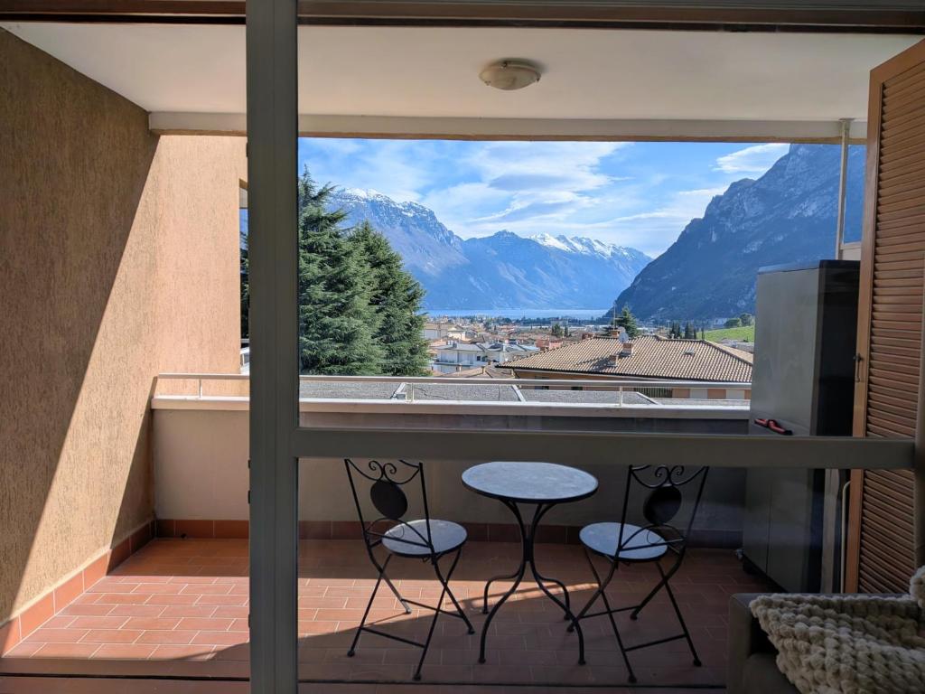 a balcony with a table and chairs and mountains at Green Oasis Garda Apartment in Riva del Garda