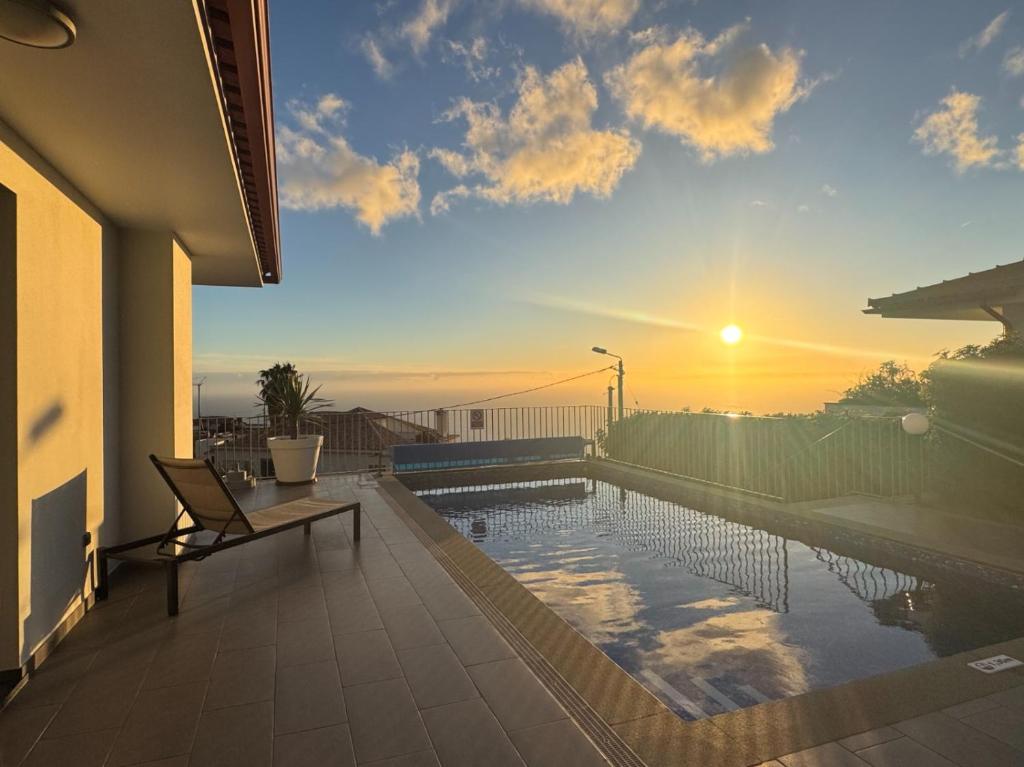 a swimming pool on the balcony of a house with the sunset at Blue Villa in Arco da Calheta