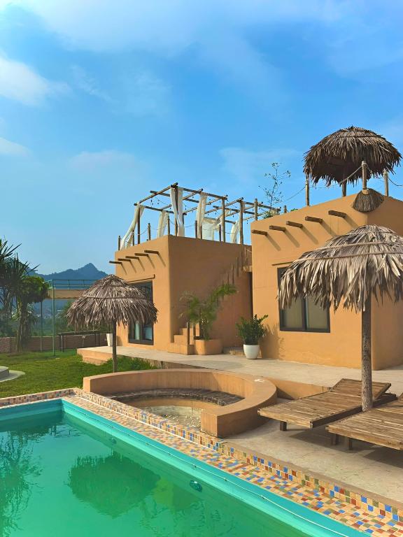 a resort with a swimming pool and umbrellas at Campo De Sole Villa Hoa Binh in Hòa Bình