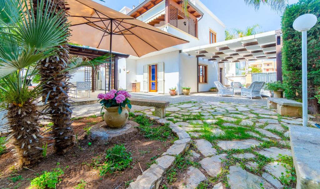 a patio with a bench and an umbrella at Baia Verde - Sea Rooms in Baia Verde