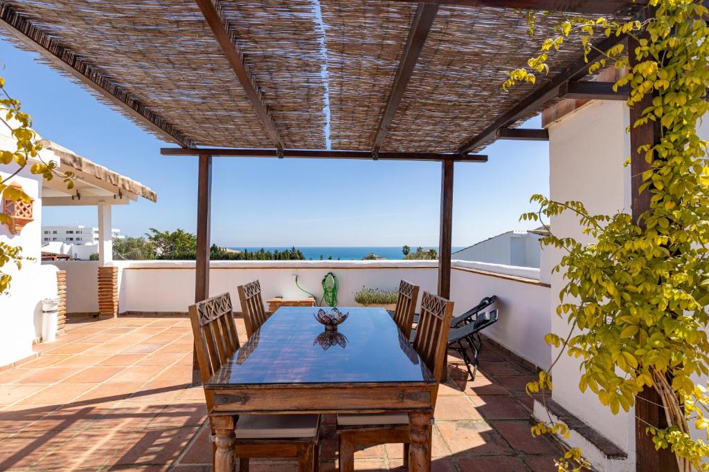 a patio with a wooden table and chairs at Authentic apartment with pool and sea view in Estepona