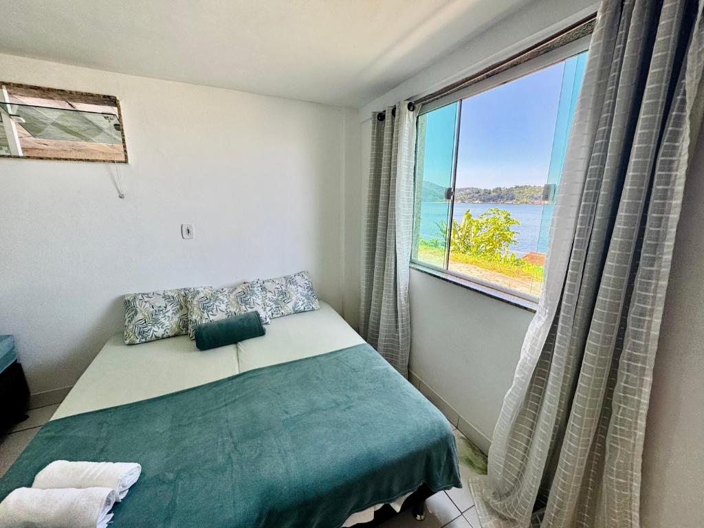 a bedroom with a bed and a large window at Casa de praia em Itacuruçá in Mangaratiba