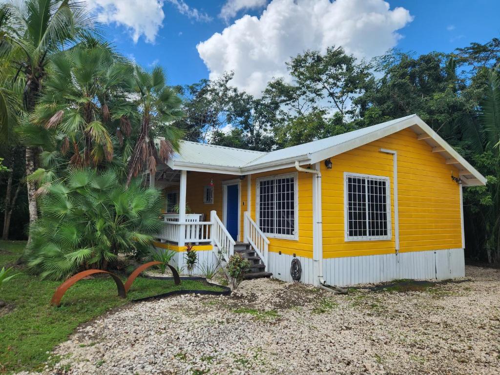 a yellow tiny house with a porch at Cozy Yellow Cottage in Spanish Lookout