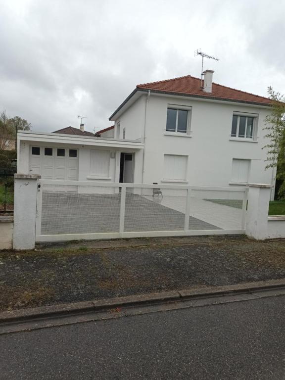 a white house with a fence in front of it at Comfortable studio dans une maison au calme in Bellerive-sur-Allier