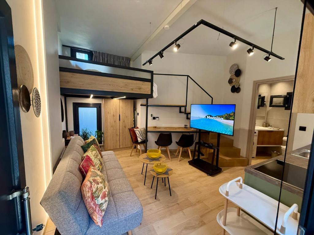 a living room with a couch and a big screen tv at La Petite Mansion, next to the city center! in Volos
