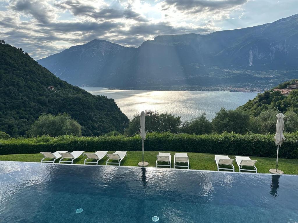 a pool with chairs and umbrellas and a view of a mountain at Residence Relais Cà dell'Era in Tremosine Sul Garda