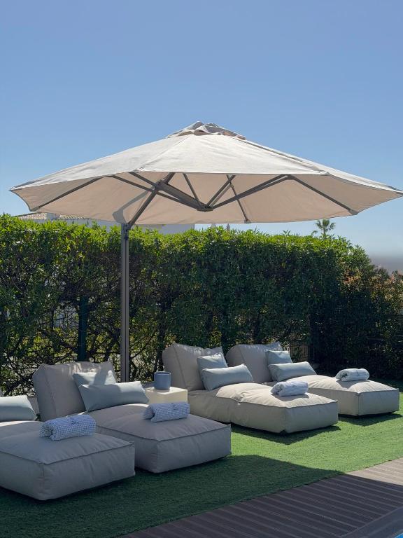 a group of white couches sitting under an umbrella at Villa Amêndoa in Loulé