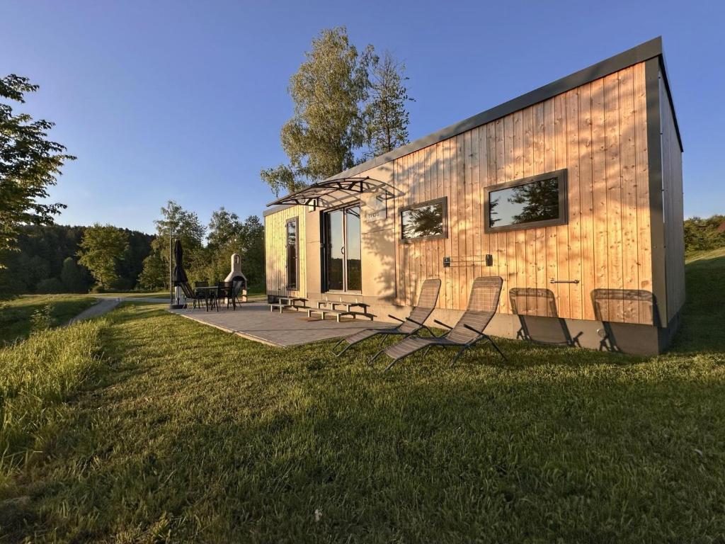 a tiny house with chairs sitting on a lawn at Feriendorf Seeblick - Tiny Chalet Nr 9 in Neunburg vorm Wald