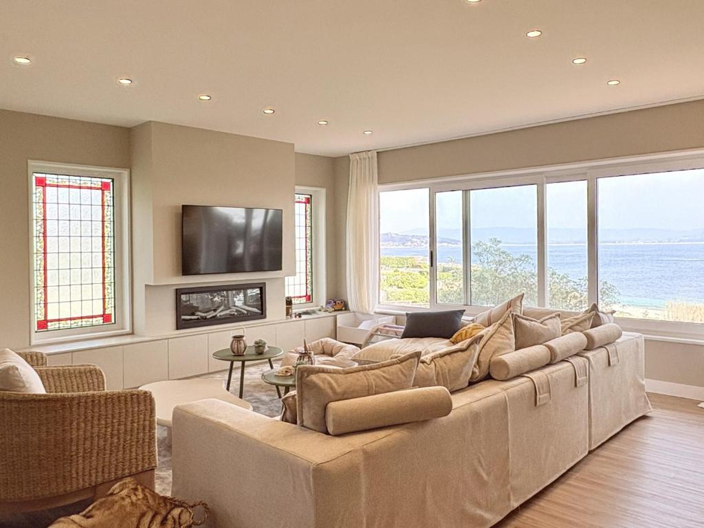 a living room with a large couch and windows at Beachfront Luxury Villa in O Grove