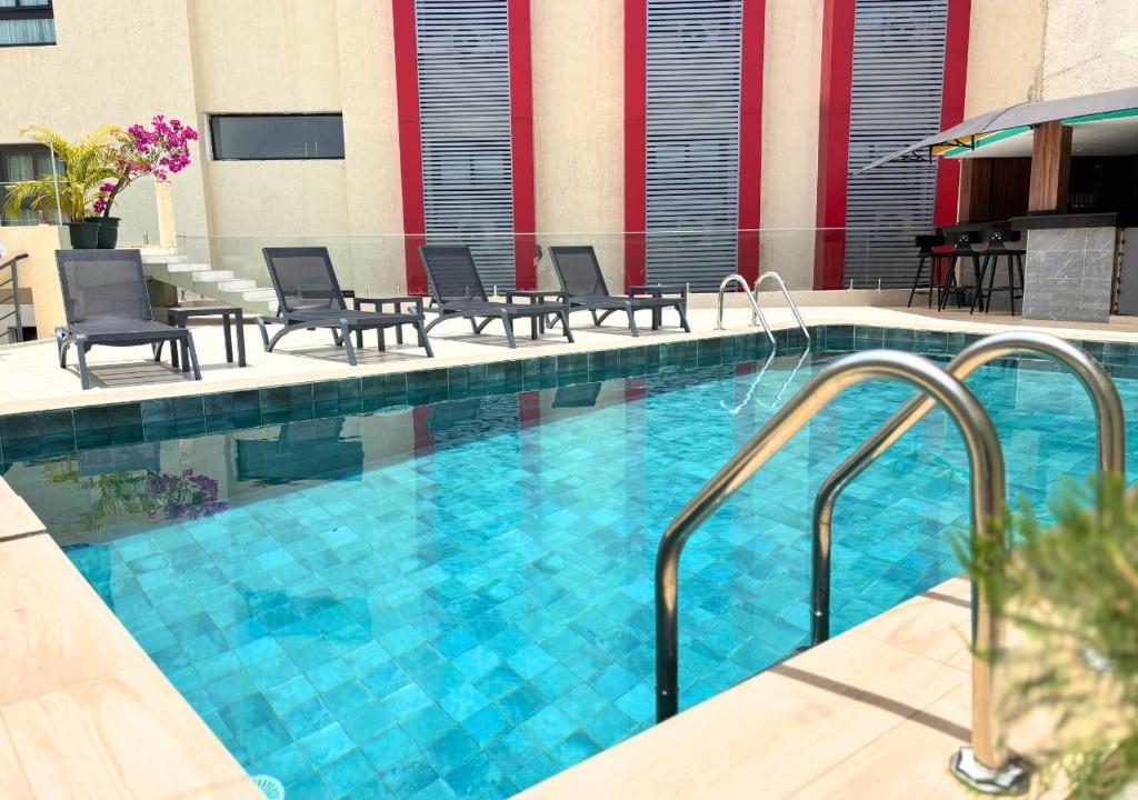 a swimming pool in a hotel with chairs and tables at Hôtel La Pivoine in Abidjan