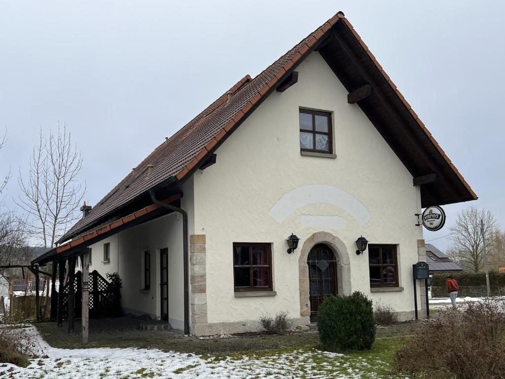 a white house with a brown roof in the snow at Gästezimmer Rittergut Inh. Christian Eickhoff in Heldburg