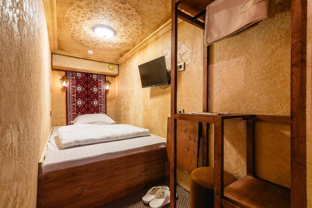 a small bedroom with a bed in a room at Alladin Capsule Hotel in Almaty