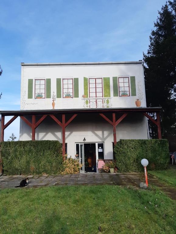 a white house with a dog sitting in front of it at Penzion Mirja in Hodkovice