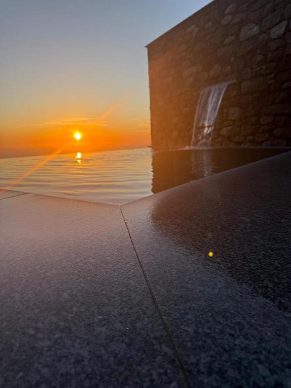 a sunset over the water next to a building at The Green Valley Porto Moniz in Achadas da Cruz