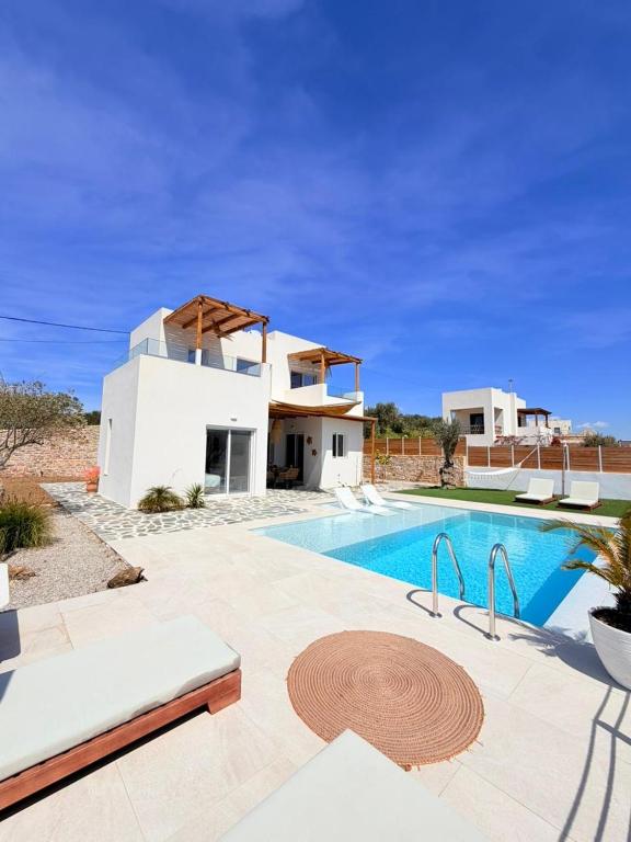a villa with a swimming pool in front of a house at Villa Livia- panoramic view with pool and beautiful garden in Pitsidia