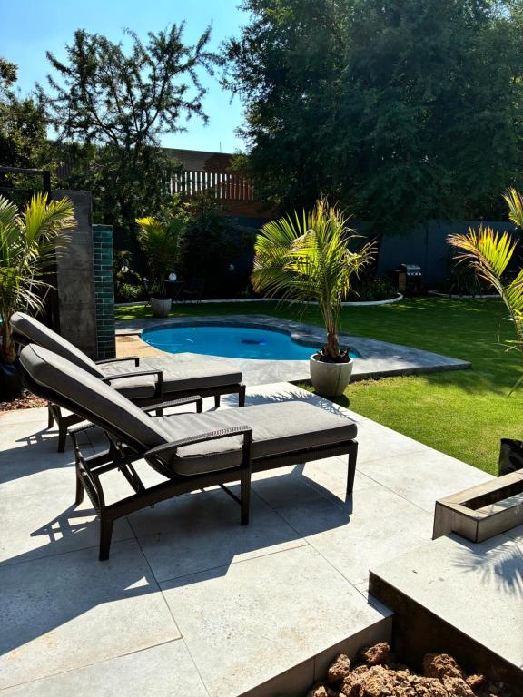 a patio with two benches and a swimming pool at Grey heron in Boksburg