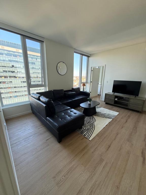 a living room with a black leather couch and a television at Luxe Apartment with Harbor views in Baltimore