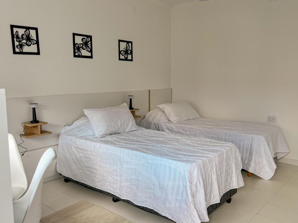 a bedroom with two beds with white sheets at Hotel Parador El Tucán in Parana