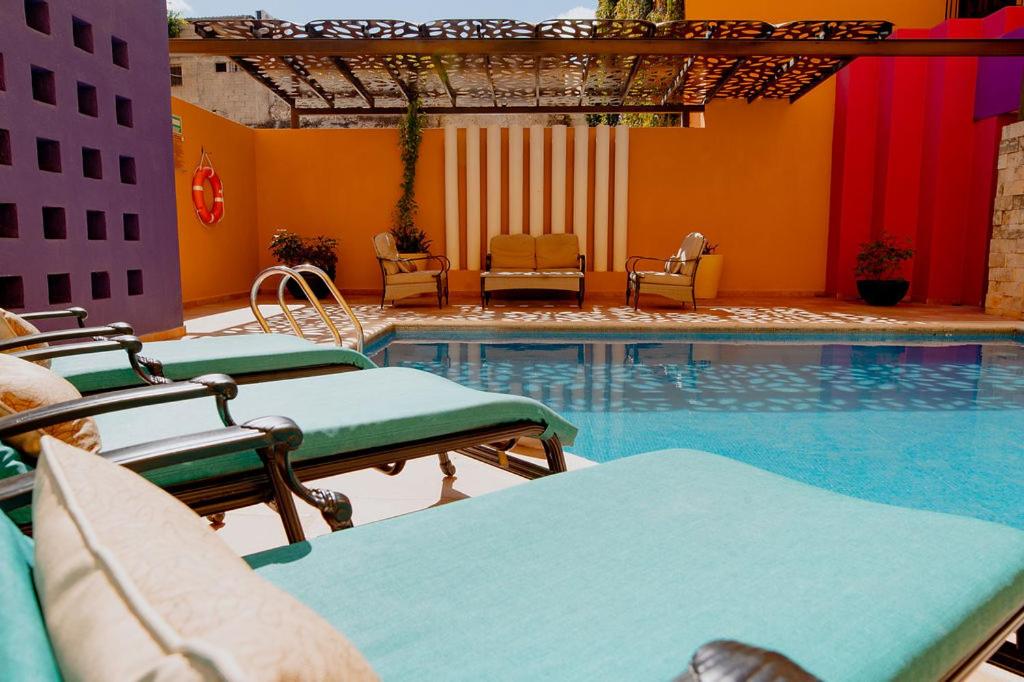 a pool with chaise lounge chairs and a swimming pool at Hotel Plaza Colonial in Campeche