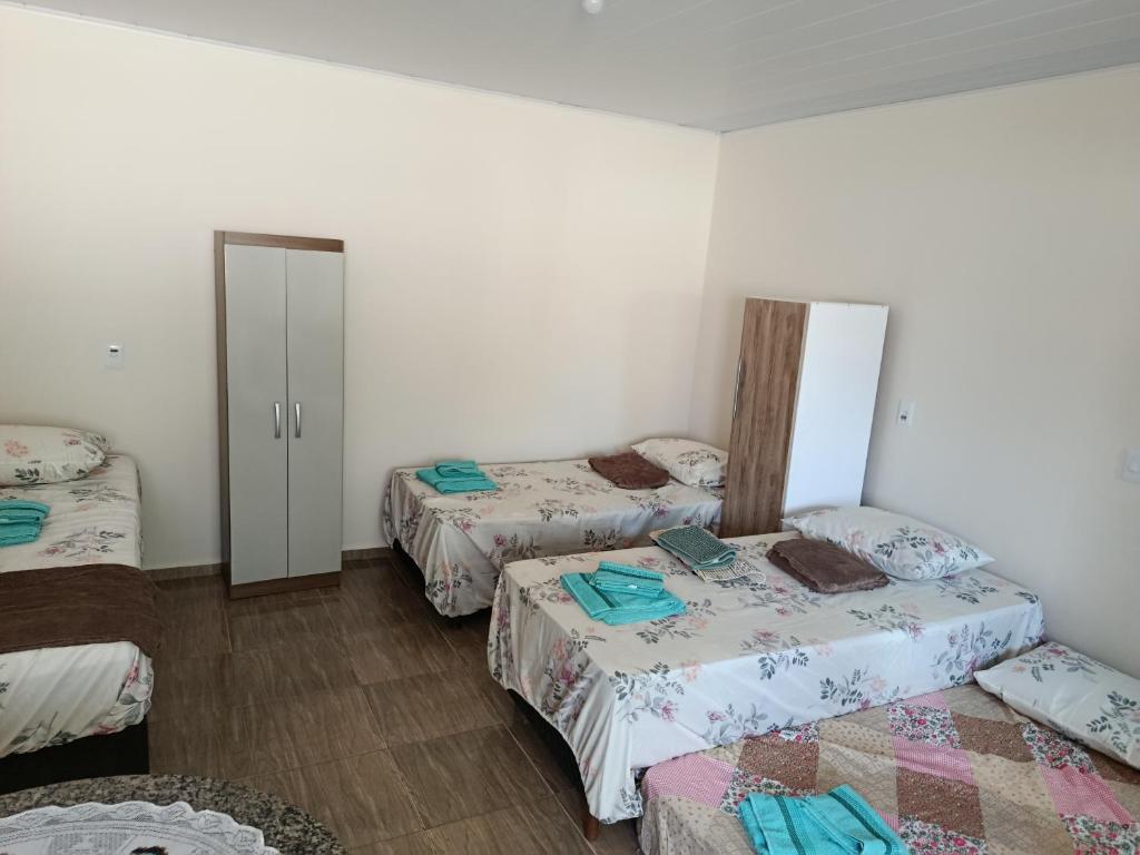 a room with three beds in it with a doorway at Pousada Paraiso in Telêmaco Borba