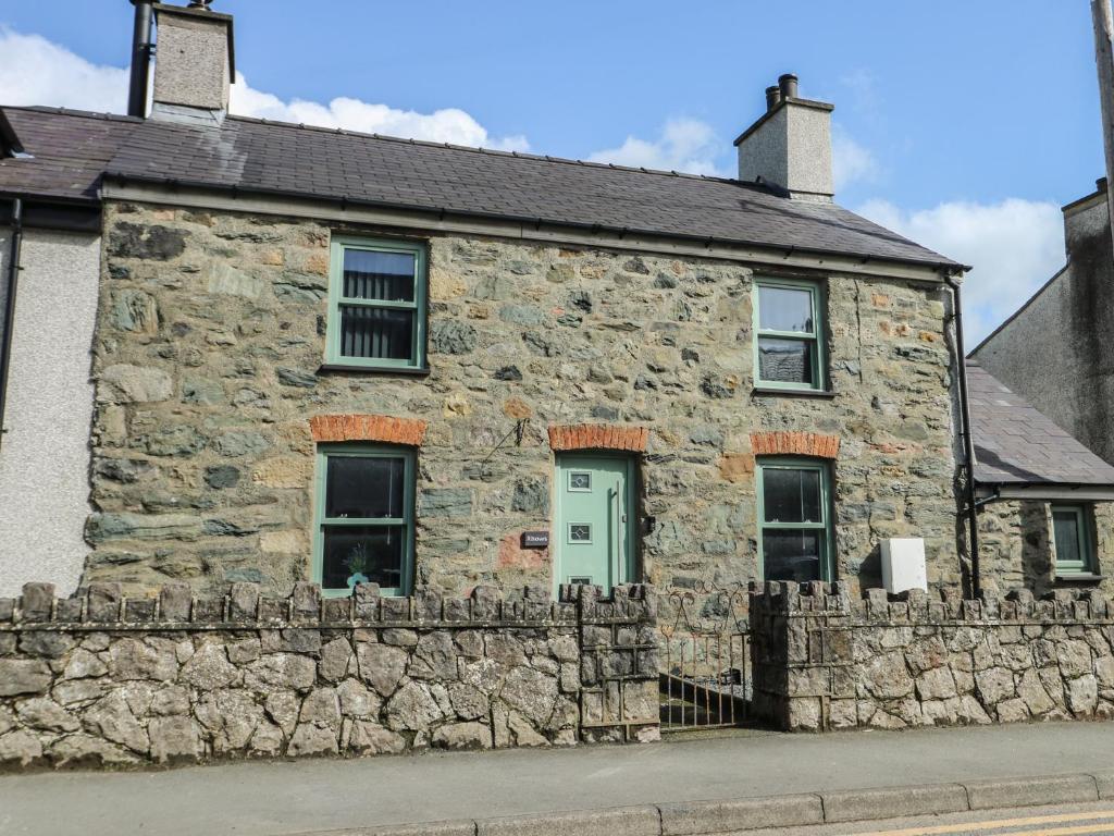 an old stone house with a stone wall at Rhows in Llanfairpwllgwyngyll