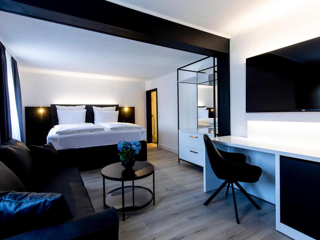 a bedroom with a bed and a living room at DORMERO Hotel Aalen in Aalen