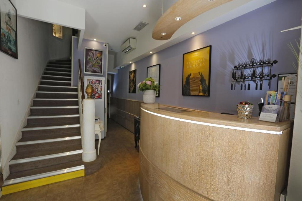 un hall avec un escalier et un comptoir de réception dans l'établissement Hôtel Alizé, à Cannes