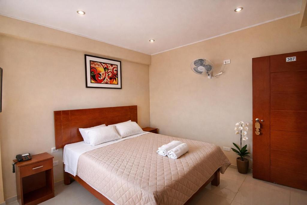 ein Schlafzimmer mit einem Bett, auf dem zwei Handtücher liegen in der Unterkunft Ikasur Hotel in Ica