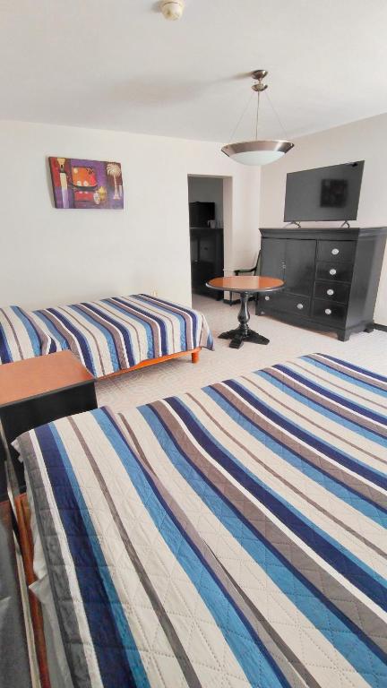 a bedroom with two beds and a desk and a table at Hotel Catalina in Torreón