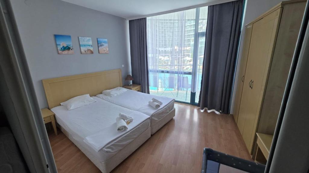 a bedroom with a white bed and a large window at Apartment in Primorsko Del Sol in Primorsko