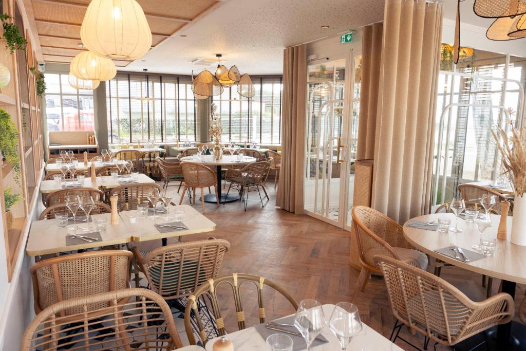 a restaurant with white tables and chairs and windows at La Villa Rose-Marie in Saint-Brevin-les-Pins