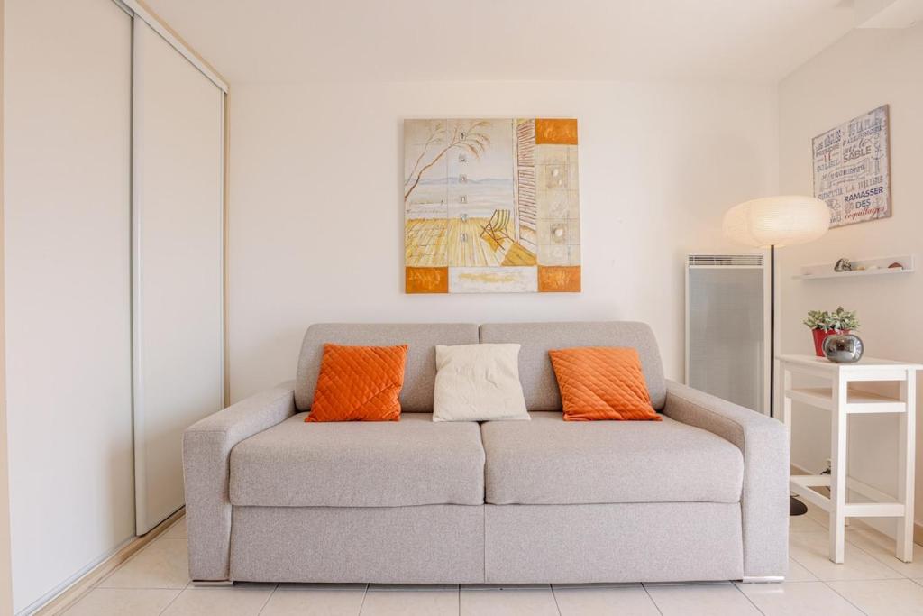 a living room with a gray couch with orange pillows at La Clé des Sternes in Camiers