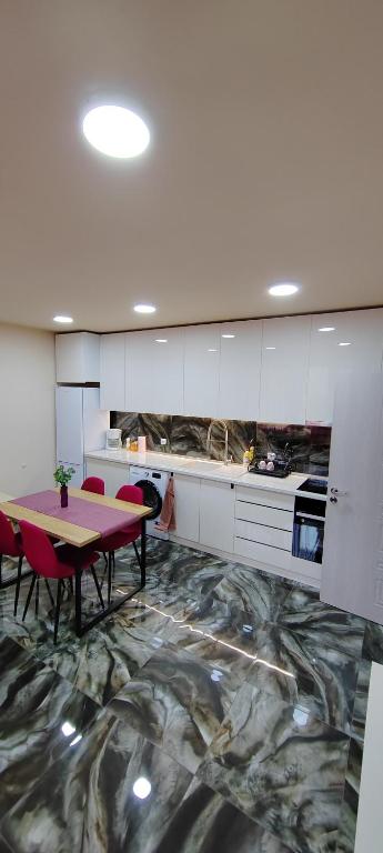 a kitchen with a table and red chairs in a room at Stylish Rose Garden Apartment with Balcony & Parking in Asenovgrad