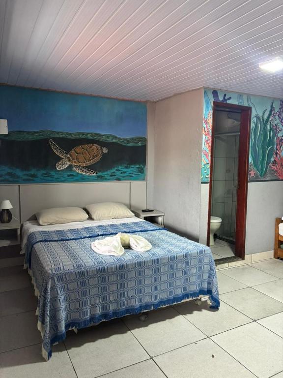 a bedroom with a bed with a turtle painting on the wall at POUSADA CÔCO MALUCO Centro Búzios in Búzios
