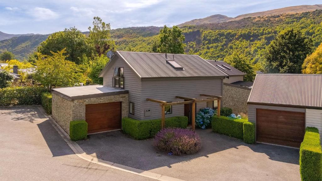 a house with a garage and mountains in the background at Chartres Retreat in Arrowtown