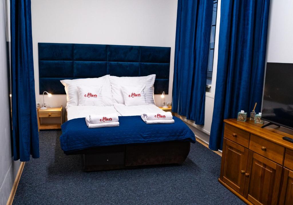 a bedroom with a bed with blue curtains and a tv at Penzión Oliver Humenné in Humenné