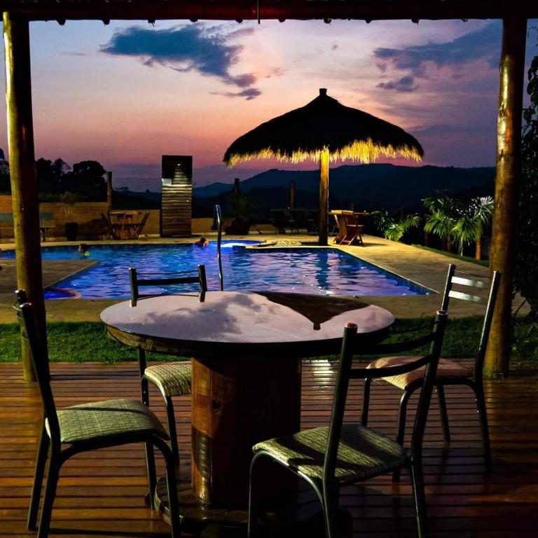 a table with chairs and an umbrella next to a pool at Pousada Morada do Sol in Socorro