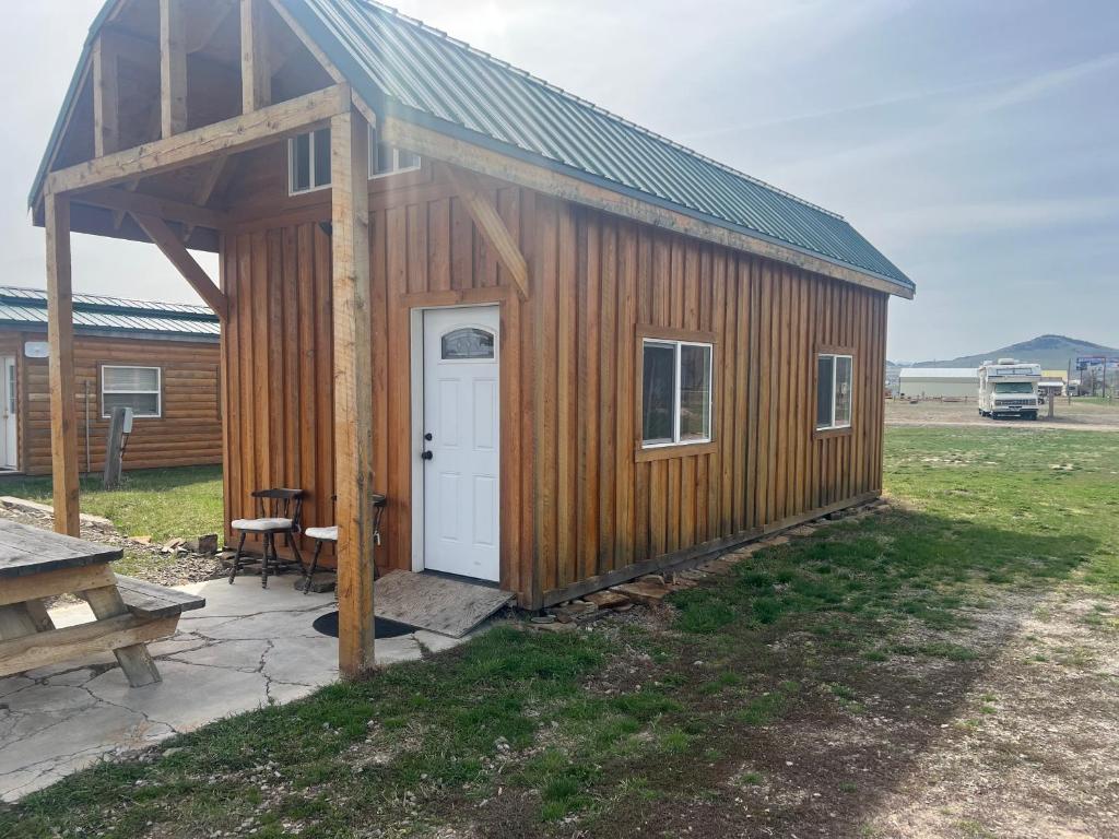 a wooden cabin with a white door and a table at Cabin 1 The Glacier in Hot Springs