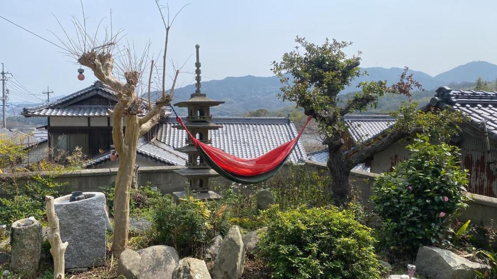 a red hammock hanging from a house in a garden at Inn Omishima in Imabari