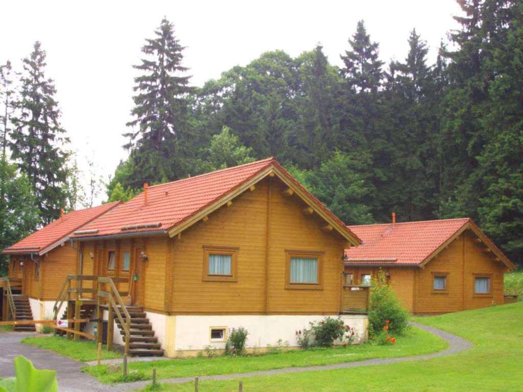 a large wooden house with a red roof at Finnische Blockhausstilhäuser im Harz in Benneckenstein