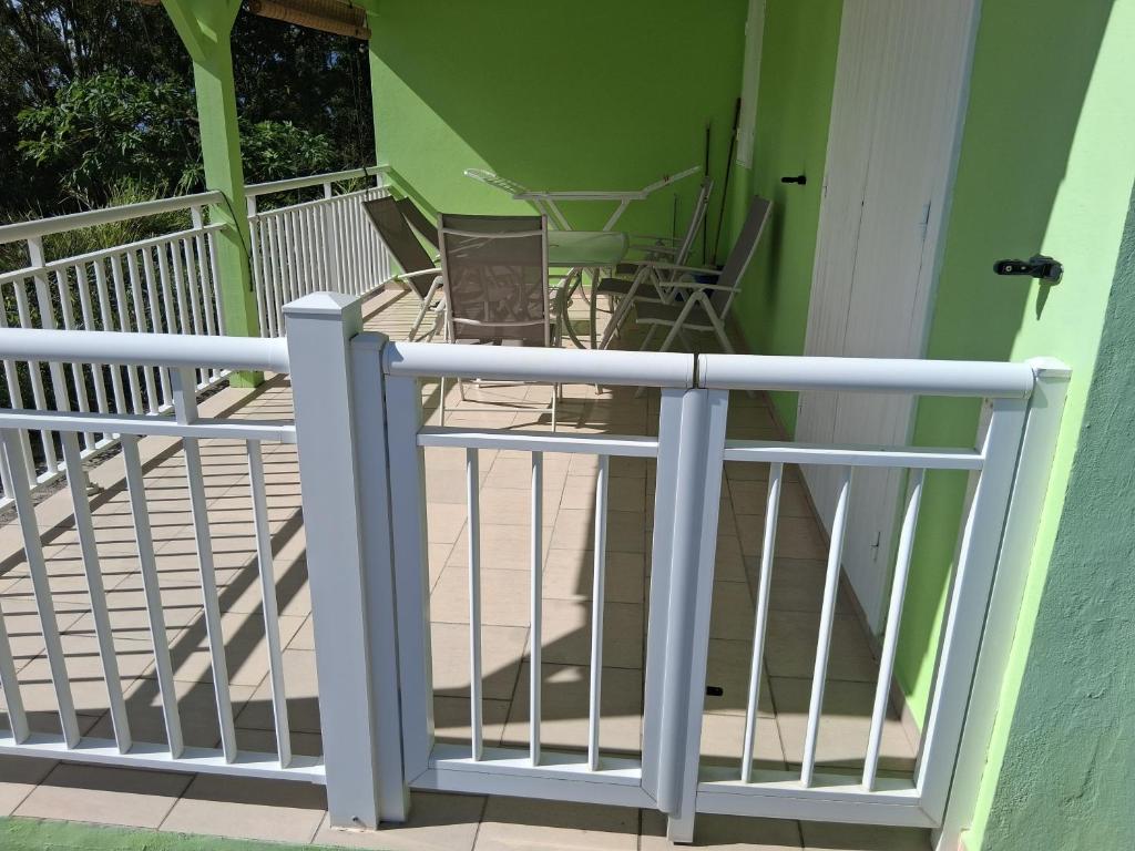 a white railing on a porch with chairs at Villa Greg in Bouillante
