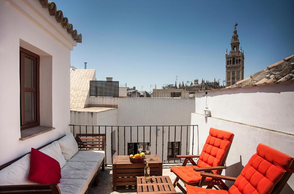 eine Terrasse mit 2 Stühlen und einem Sofa auf dem Balkon in der Unterkunft Angeles House in Sevilla