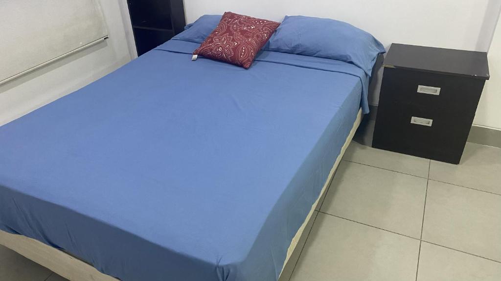 a bed with a blue blanket and a pillow on it at Habitación en el Tornero in SamborondÃ³n