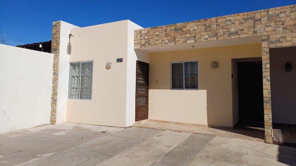 a white house with a door and a building at Casa Sendero in Los Mochis