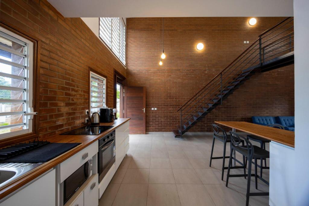 a kitchen with a brick wall and a staircase at Macapa - Destination Guyane in Macouria