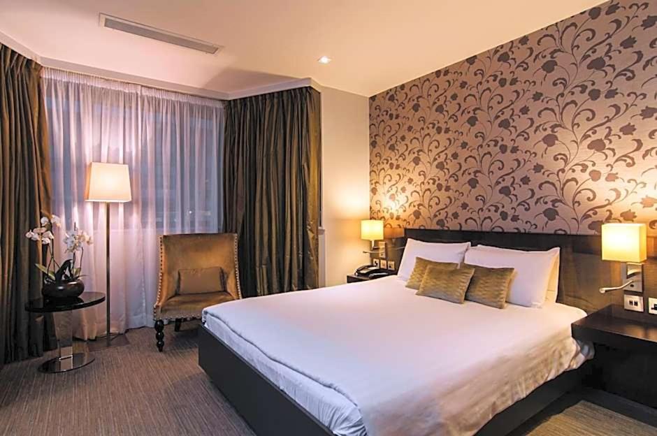 a hotel room with a large bed and a chair at The Hide London in Hendon