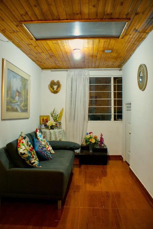 a living room with a green couch and a wooden ceiling at Hospedaje Patty Cajicá in Cajicá