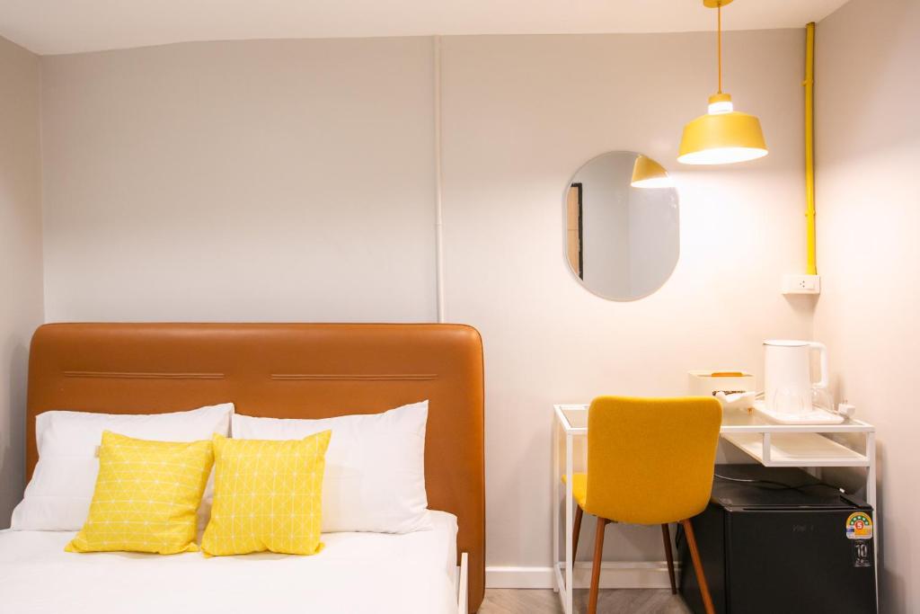 a bedroom with a bed with yellow pillows and a yellow chair at Siri Space สิริ สเปซ in Ban Khlong Nung (1)