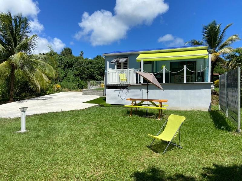 a house with a yard with a table and a yellow chair at Exceptional bungalow with private pool in Rivière-Pilote