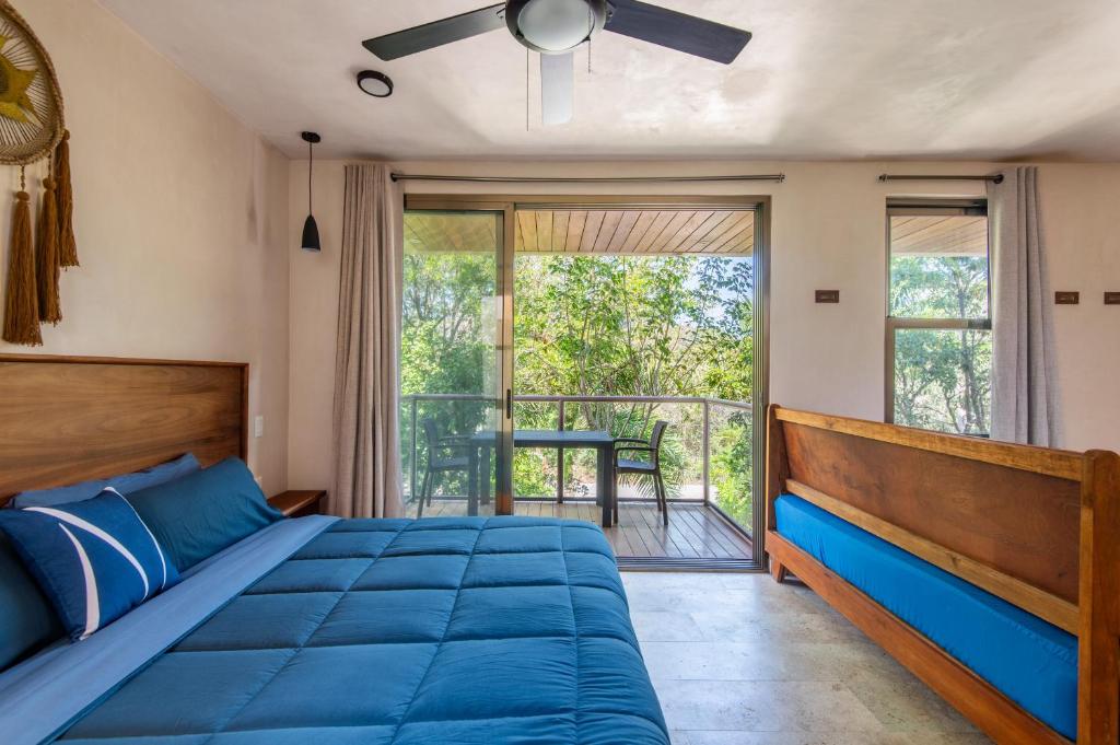 a bedroom with a blue bed and a balcony at Jungle Loft Suite with Terrace & Natural Light - Santuario Hotel Boutique in Chemuyil